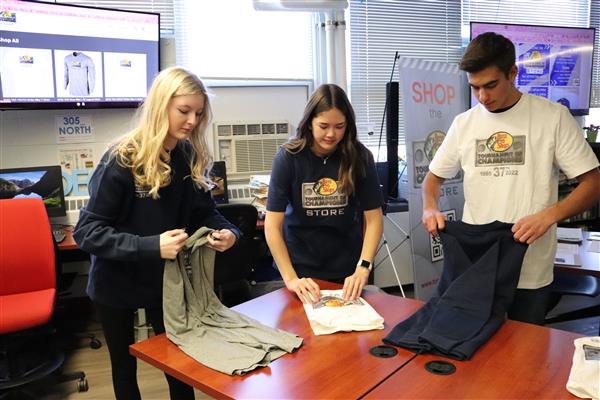 students folding clothes in school store