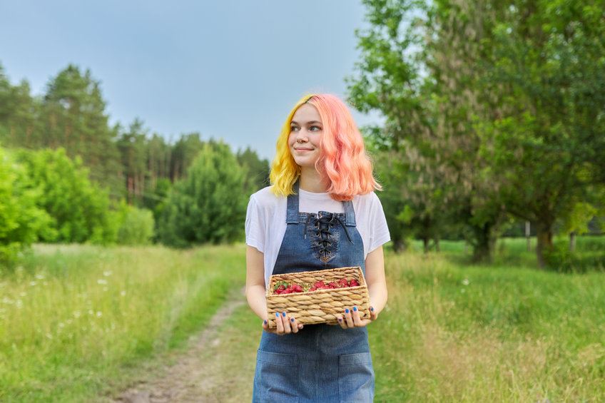 Female student working on a farm holding strawberries Female student working on a farm holding strawberries