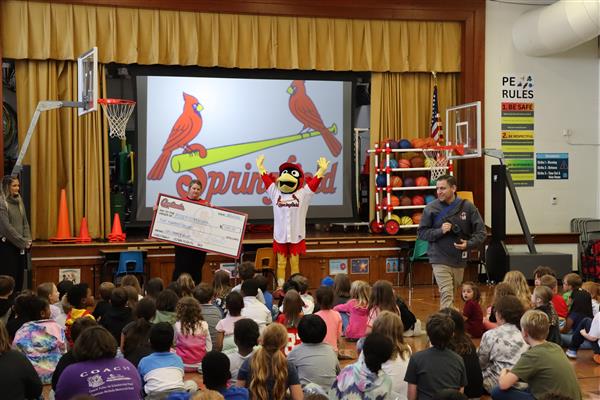 Springfield Cardinals mascot stands in front of of kids, next to a woman holding a giant check.