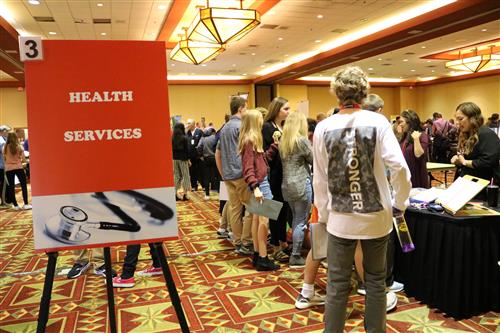 Health Services career fair sign with students at a booth 